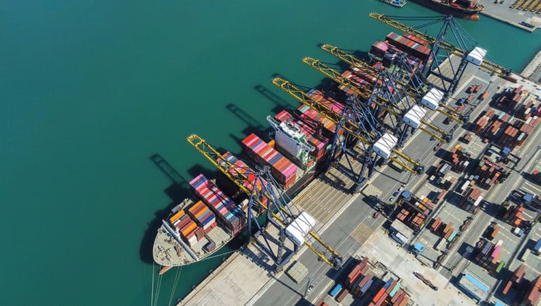 Birds eye view of a cargo ship at a dock with many conex containers