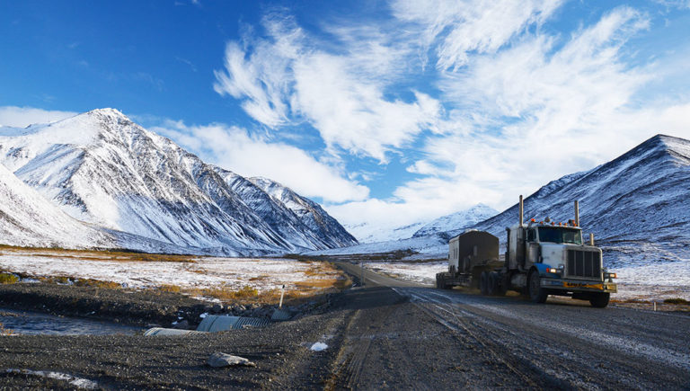 truck on the road surrounded by snowy mountains